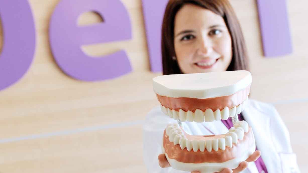 Doctora de la Clínica BioDental Blanes mostrando una maqueta dental en la clínica de Blanes